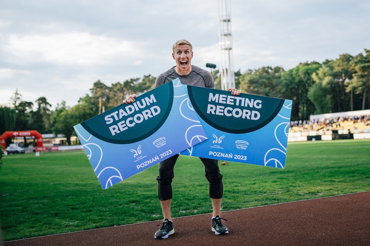 Piotr Lisek holds up a plaque with the world record and stadium record on it